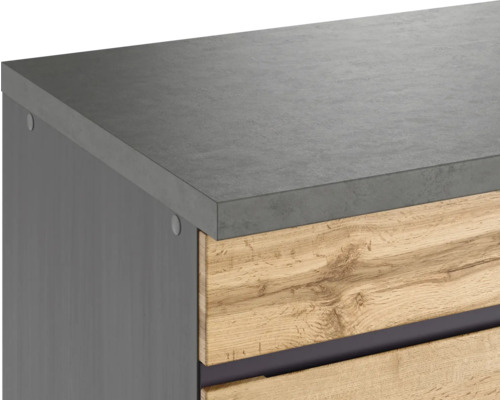 Detailaufnahme eines Möbelstücks mit grauer Arbeitsplatte und Holzschubladen