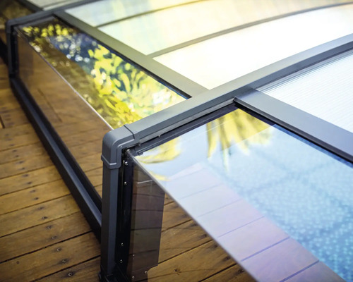 Detailansicht einer Poolüberdachung aus Glas und Aluminium auf einem Holzdeck.
