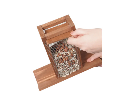 Vogelhaus aus Holz mit Futternetz und Hand beim Öffnen