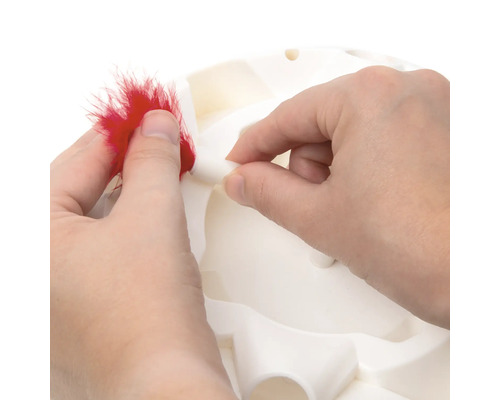 Eine Person befestigt eine Feder an einem interaktiven Katzenspielzeug.