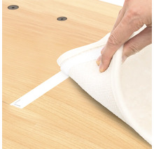 Hand befestigt einen Teppich mit Klettband auf einer Oberfläche.