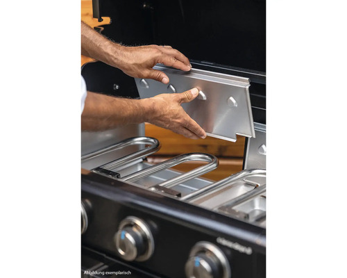 Eine Person setzt eine Edelstahlplatte in einen Gasgrill ein.