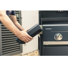 Person setzt Batterie in Gasgrill ein