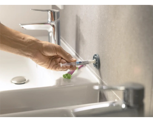 Eine Person befestigt einen Dübel mit Injektionsmörtel im Badezimmer.