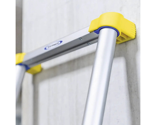 Detailansicht einer Aluminiumleiter mit gelben Füßen und einer Wand im Hintergrund