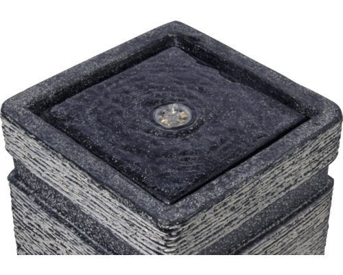 Detailaufnahme eines quadratischen Gartenbrunnens mit Beleuchtung