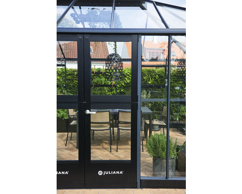 Gewächshaus mit Glastüren und Juliana Logo. Im Inneren befindet sich ein Esstisch mit Stühlen.