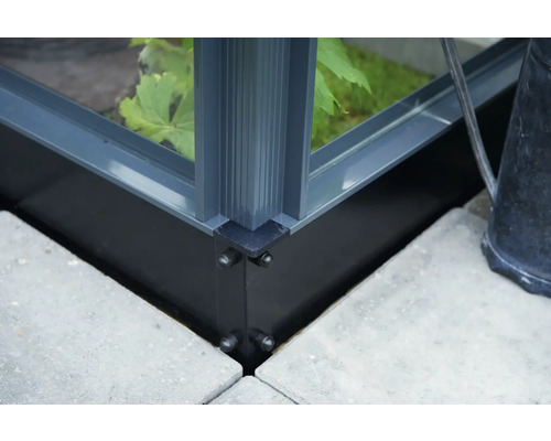Detailansicht einer Gewächshausecke mit Aluminiumrahmen auf Betonplatten
