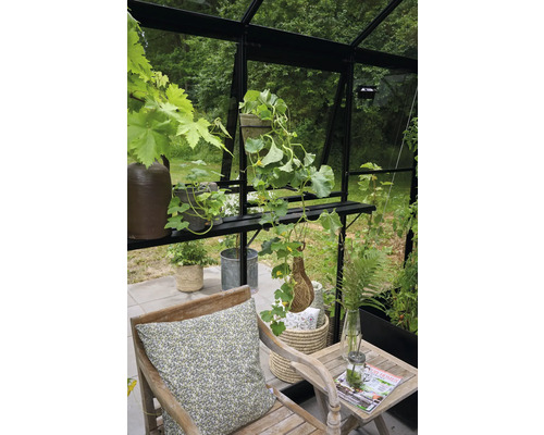 Gemütliche Sitzecke in einem Gewächshaus mit Pflanzen und Gartenmöbeln