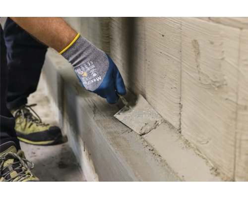 Handwerker trägt Putz mit einer Maurerkelle auf eine Wand auf