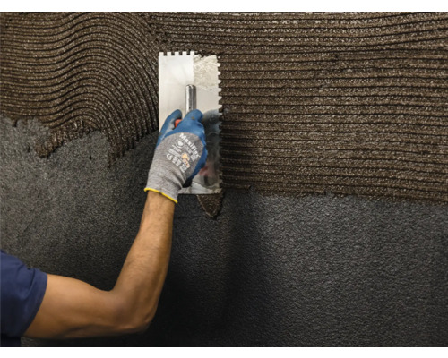 Auftragen von Klebstoff mit einer Zahnspachtel auf eine Oberfläche