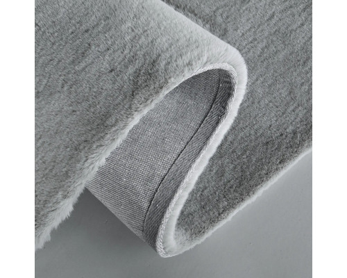 Detailansicht eines grauen Hochflorteppichs mit Textilrücken