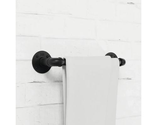 Handtuchhalter aus Metallrohr mit Handtuch an einer Ziegelwand