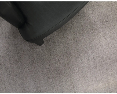 Detailaufnahme eines schwarzen Sessels auf einem grauen Teppich