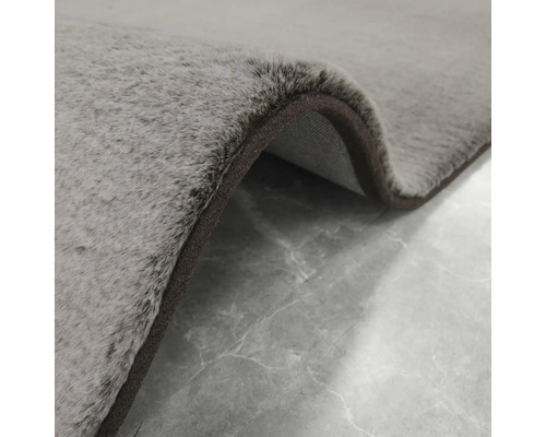 Nahaufnahme eines grauen Teppichs mit braunem Rand