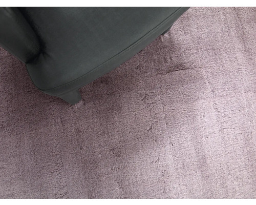 Nahaufnahme eines Hochflor Teppichs mit Sesselbein