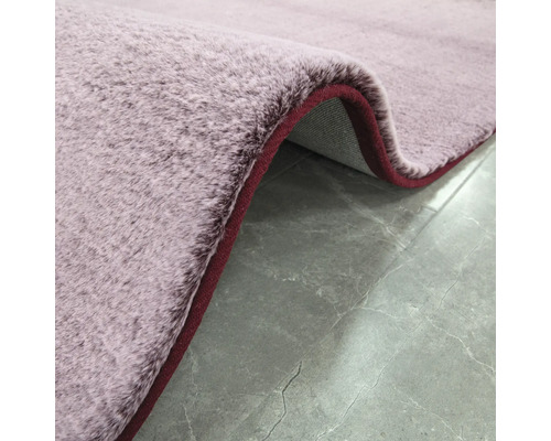 Hochflor Teppich mit roter Kante auf Steinfliesen