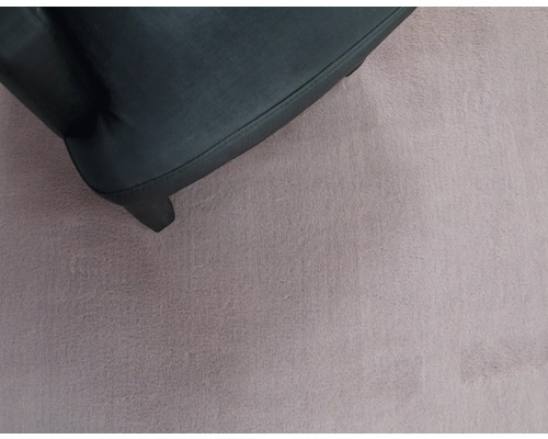 Detailansicht eines schwarzen Möbelbeins auf einem Teppich