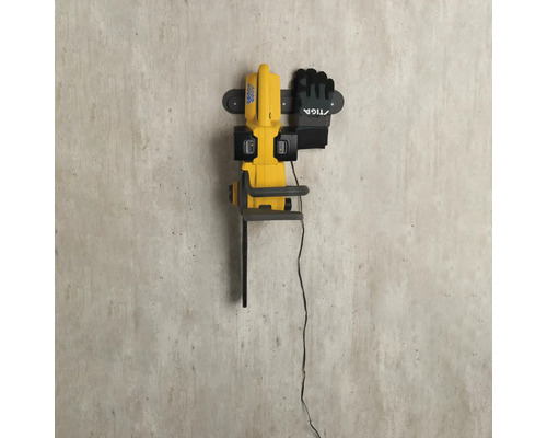 Gelbe Elektro-Kettensäge mit Arbeitshandschuhen an einer Wandhalterung