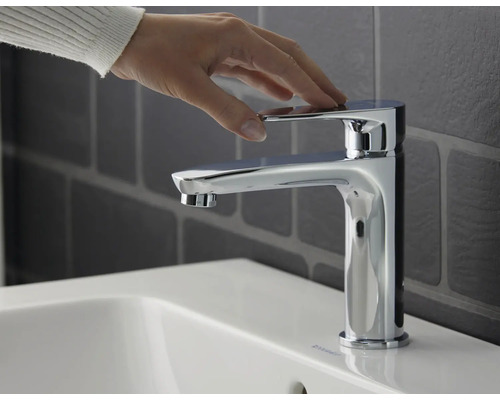 Einhandmischer auf einem Waschbecken mit einer Hand auf dem Hebel.