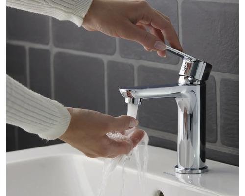 Frau wäscht sich die Hände unter einem Chrom-Waschtischmischer.