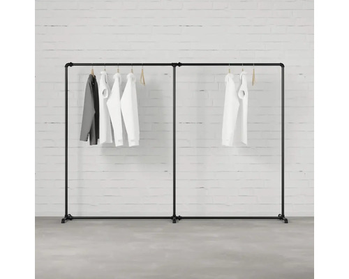 Schwarzer Kleiderständer mit daran hängender Kleidung vor einer Ziegelwand