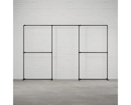 Schwarze, modulare Kleiderständer-Garderobe aus Metallrohren vor einer weißen Ziegelwand.