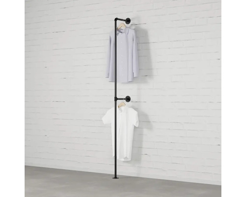 Kleiderständer aus Eisenrohr mit zwei daran hängenden Hemden vor einer weißen Ziegelwand