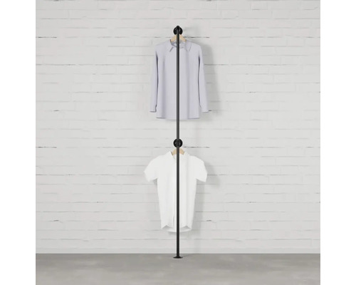 Schwarzer Kleiderständer mit zwei Kleidungsstücken vor einer Backsteinmauer