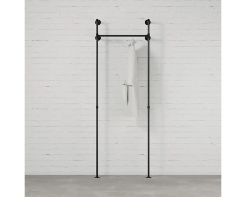 Schwarze Kleiderstange aus Rohren mit einem Kleidungsstück vor einer Ziegelwand