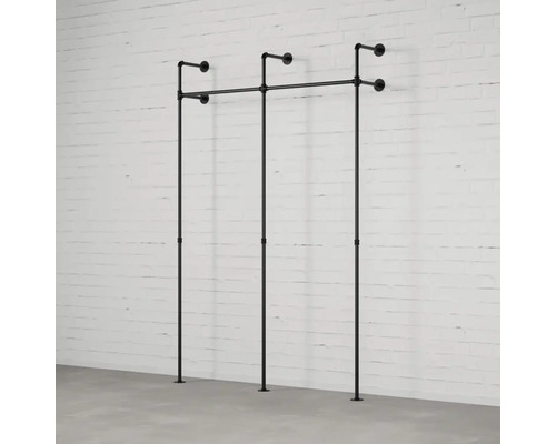 Wandgarderobe aus Rohren vor einer Ziegelwand