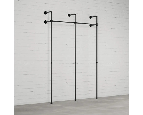 Wandgarderobe aus Rohren vor einer Ziegelwand