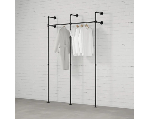 Freistehende Kleiderständer aus Rohren mit Kleidung vor einer Ziegelwand