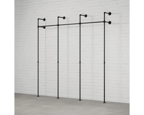 Schwarzer Kleiderständer aus Metallrohren vor einer weißen Ziegelwand