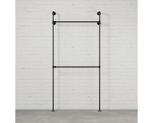 Schwarze Kleiderstange aus Metall vor einer Ziegelwand