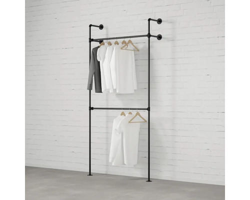 Zweireihige Kleiderstange aus Metallrohr mit daran hängender Kleidung vor einer Ziegelwand