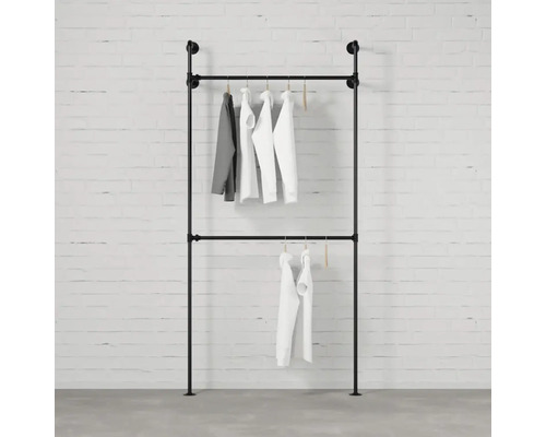 Kleiderständer aus Rohren mit hängender Kleidung vor einer Ziegelwand