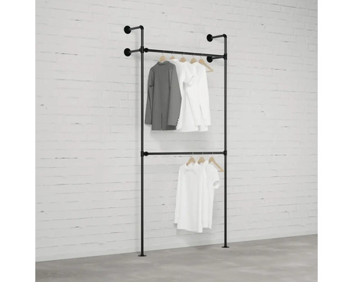 Schwarzer, zweistöckiger Kleiderständer mit Kleidung an der Wand