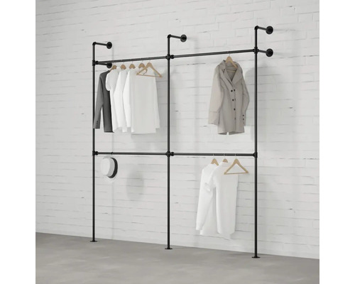 Kleiderständer aus Rohren mit daran hängender Kleidung vor einer Backsteinwand