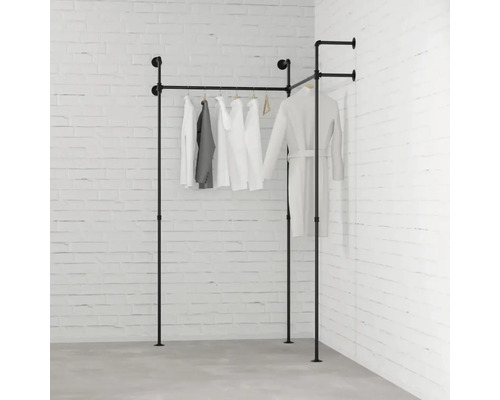 Schwarzer Kleiderständer aus Metallrohr mit Kleidung vor einer Ziegelwand