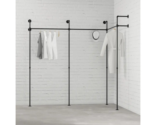 Schwarzes Kleiderstangensystem mit Kleidung vor einer weißen Ziegelwand