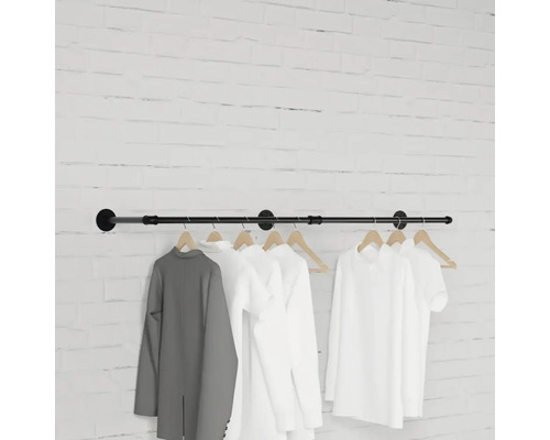 Wandgarderobe mit daran hängenden Kleidungsstücken vor einer Backsteinmauer