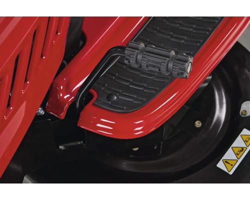 Detailansicht eines Rasentraktors mit Fußpedal und Warnhinweisen auf dem Mähwerk