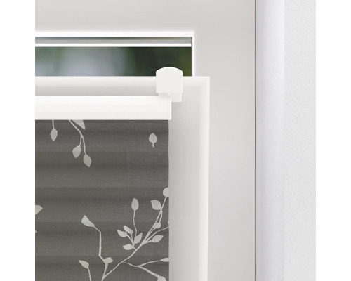 Nahaufnahme eines grauen Plissees mit Blätterdesign am Fenster