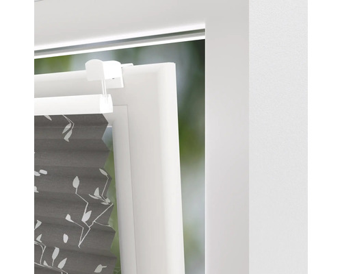 Detailansicht eines grauen Plissees mit Pflanzenmuster am Fenster