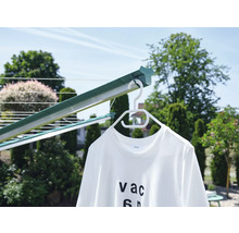 Wäschespinne mit einem weißen T-Shirt auf einem Kleiderbügel im Garten.