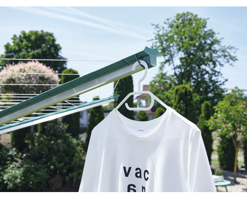Wäschespinne mit einem weißen T-Shirt auf einem Kleiderbügel im Garten.