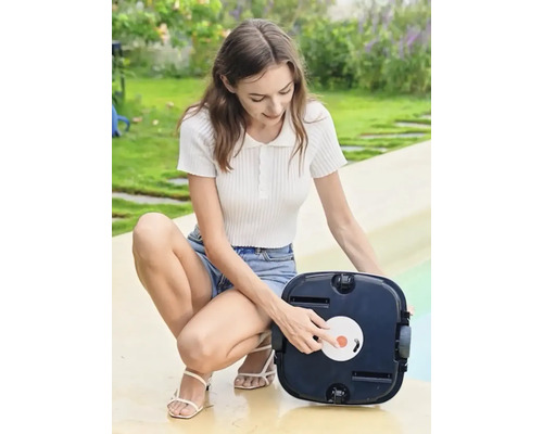 Frau bedient einen automatischen Poolreiniger im Garten.