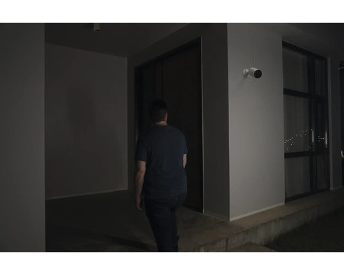 Mann geht in ein Haus unter einer Überwachungskamera