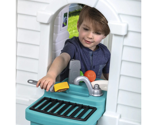 Junge spielt mit einer Spielküche im Freien mit Spüle, Grill und Spielzeug Lebensmitteln